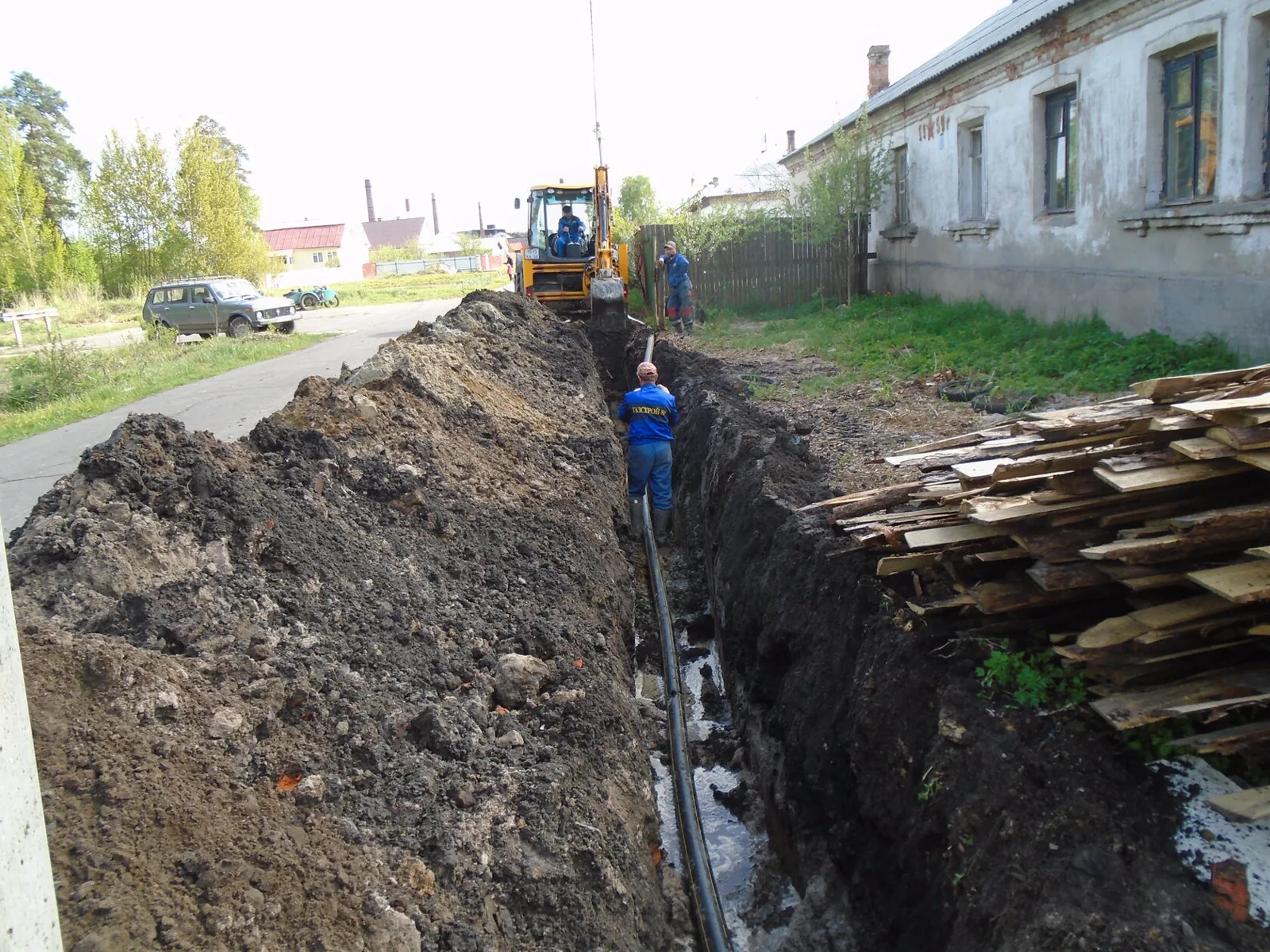 Бригада ГАЗСТРОЙ 89 укладывает полиэтиленовый газопровод в траншею вдоль улицы
